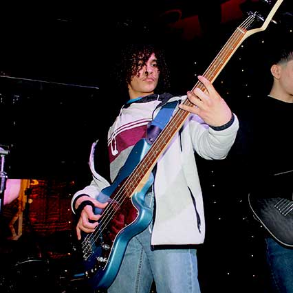Student playing bass guitar on stage